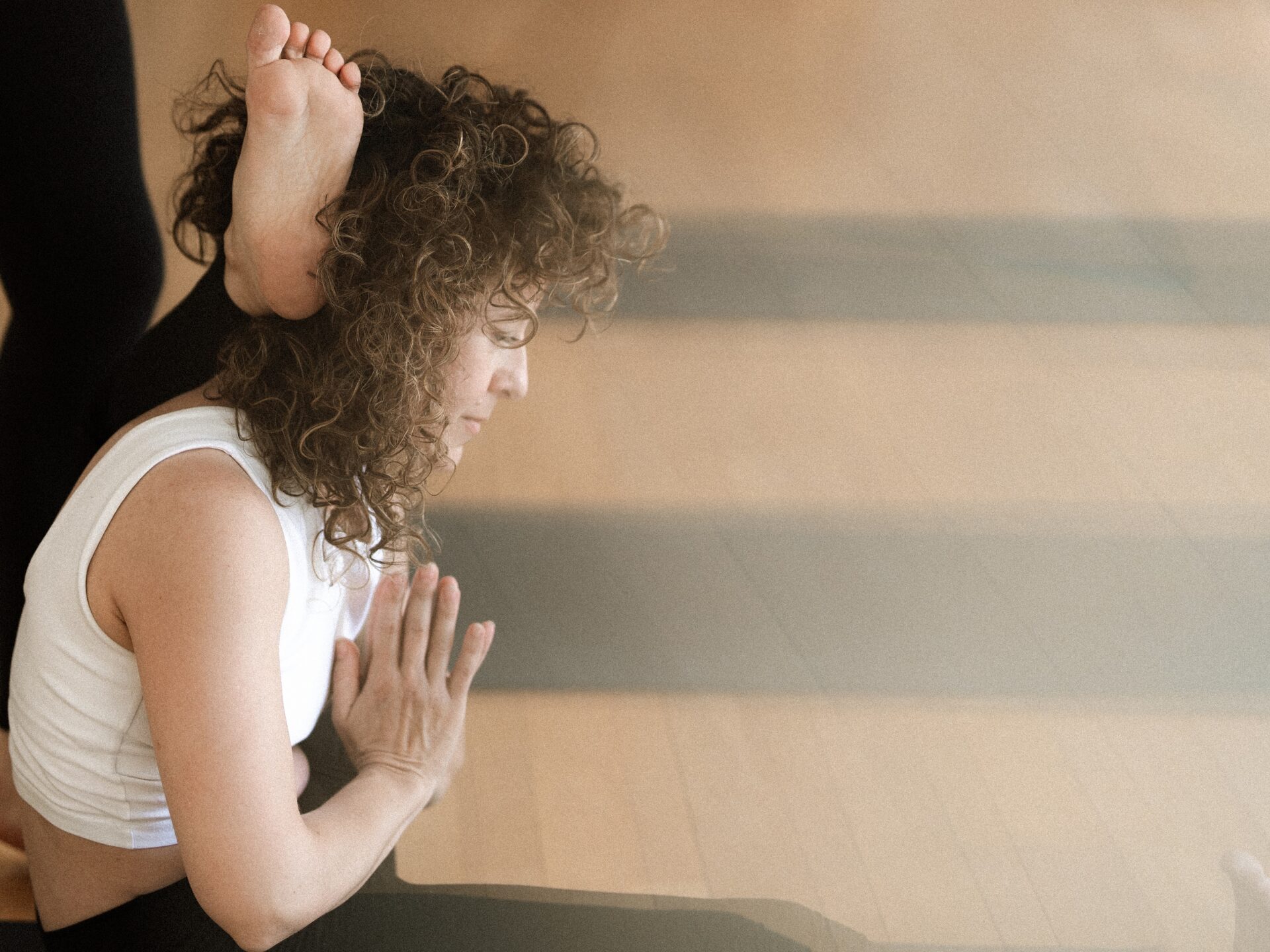Pose du pied derrière la tête, Ekapada sirsasana. Une professeur fait cette posture dans un studio de yoga à Nantes.